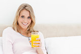 Woman looking forward and smiling with a glass of orange juice i