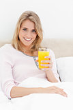Close up, Woman sitting in bed, with a glass of orange juice in 