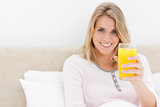 Woman holding a glass of orange juice while smiling and looking 