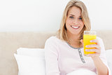 Woman holding a glass of orange juice while smiling and looking 