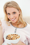 Close up, woman with raised spoon of cereal smiling and looking 