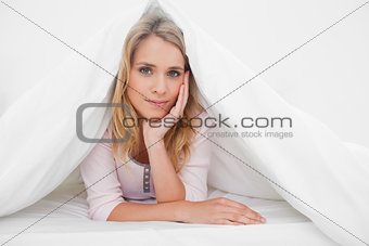 Woman lying under a quilt with her hand supporting her head