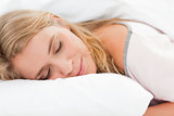 Woman lying in bed, her head on a pillow and eyes closed