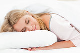 Woman lying in bed with her head resting on the pillow and her h