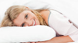 Woman lying in bed, her head on the pillow and eyes open while s