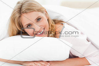 Woman lying in bed, her hands under the pillow, her head raised 