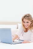 Woman lying on the bed, laptop beside her as she looks forward s