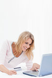 Woman smiling and looking at laptop screen with credit card in h