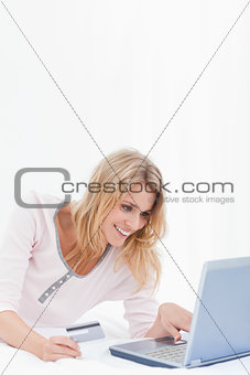 Woman smiling and looking at laptop screen with credit card in h
