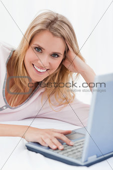 Close up, woman with her hand on her laptop, smiling and looking