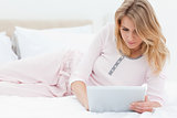 Woman lying on the bed, while using a tablet pc