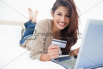 Woman smiling and looking ahead as she uses her laptop, and cred