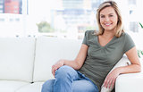 Woman sitting on the couch with crossed legs and a smile