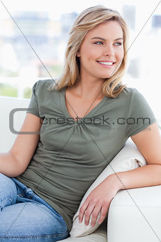 Woman looking to her side while smiling and sitting on the couch