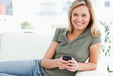 Woman smiling and looking in front of her as she uses her phone