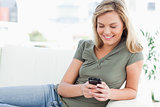 Woman smiles while using her phone and lying on the couch