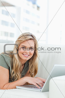 Close up, woman smiling and looking forward with her laptop in f