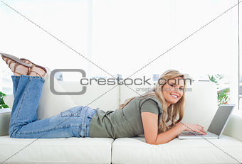 Woman smiling as she looks forward, legs raised and using her la