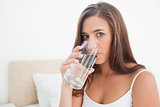Woman looking forward drinking from a glass of water