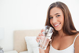 Woman smiling as she holds a glass of water,