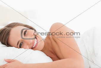 Woman lying in bed with a bright smile