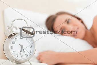 Woman in bed with her alarm clock beside her showing the time
