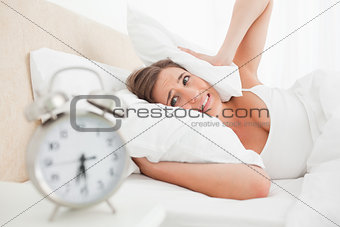 Woman covering her ears with a pillow