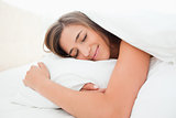 Woman sleeping in bed, with a smile and her head on the pillow