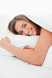 Woman lying in bed, awake, smiling as she looks forward