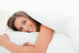 Woman in bed smiling, awake and looking straight ahead