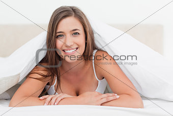 Woman lying at the end of the bed, smiling as she looks forward