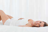 Woman lying on the bed on her back, smiling and looking forward