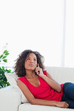 Woman making a call, while looking up, sitting on the couch