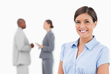 Smiling saleswoman with talking colleagues behind her