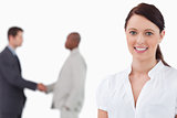 Smiling saleswoman with hand shaking colleagues behind her