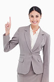 Smiling young businesswoman pointing up