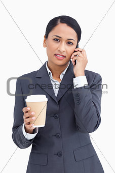 Close up of serious saleswoman with paper cup and cellphone