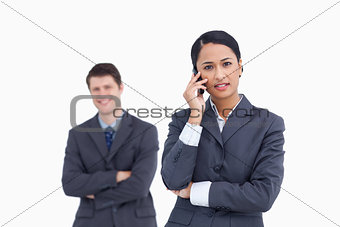 Close up of serious saleswoman on the phone with co-worker behin