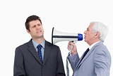 Close up of mature businessman with megaphone yelling at colleag