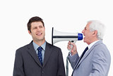 Close up of mature businessman with megaphone yelling at employe