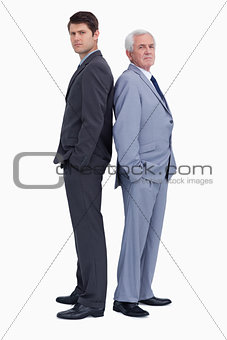 Serious businessmen standing back to back