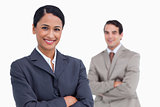Smiling saleswoman with arms folded and colleague behind her