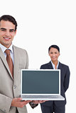 Laptop being presented by smiling salesman with colleague behind