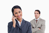 Smiling saleswoman on her mobile phone and colleague behind her