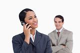 Smiling saleswoman on her mobile phone and co-worker behind her
