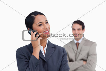 Smiling saleswoman on her mobile phone and co-worker behind her