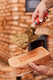 Masonry heater builder hand with brick and trowel