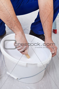 Worker stirring the paint - closeup on hands