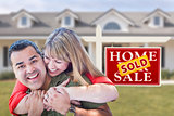 Mixed Race Couple in Front of Sold Real Estate Sign and House