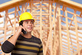 Hispanic Male Contractor on Phone in Front of House Framing